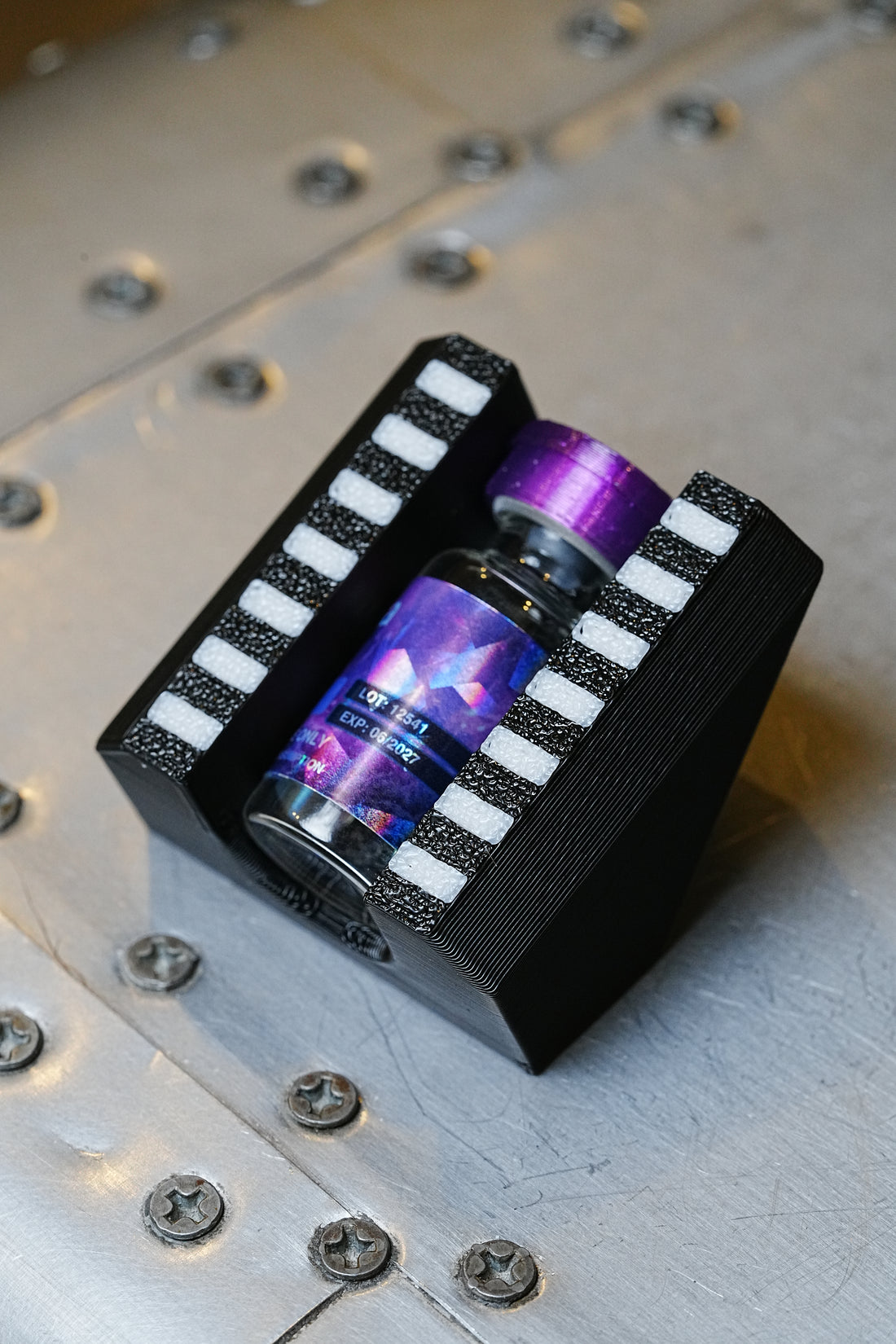 Black 3 mL vial labeling jig holding a vial with a custom printed label applied