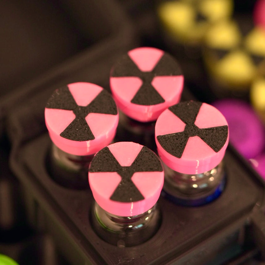 Radio Pink flexible vial caps with a black radiation symbol, close-up on capped vials