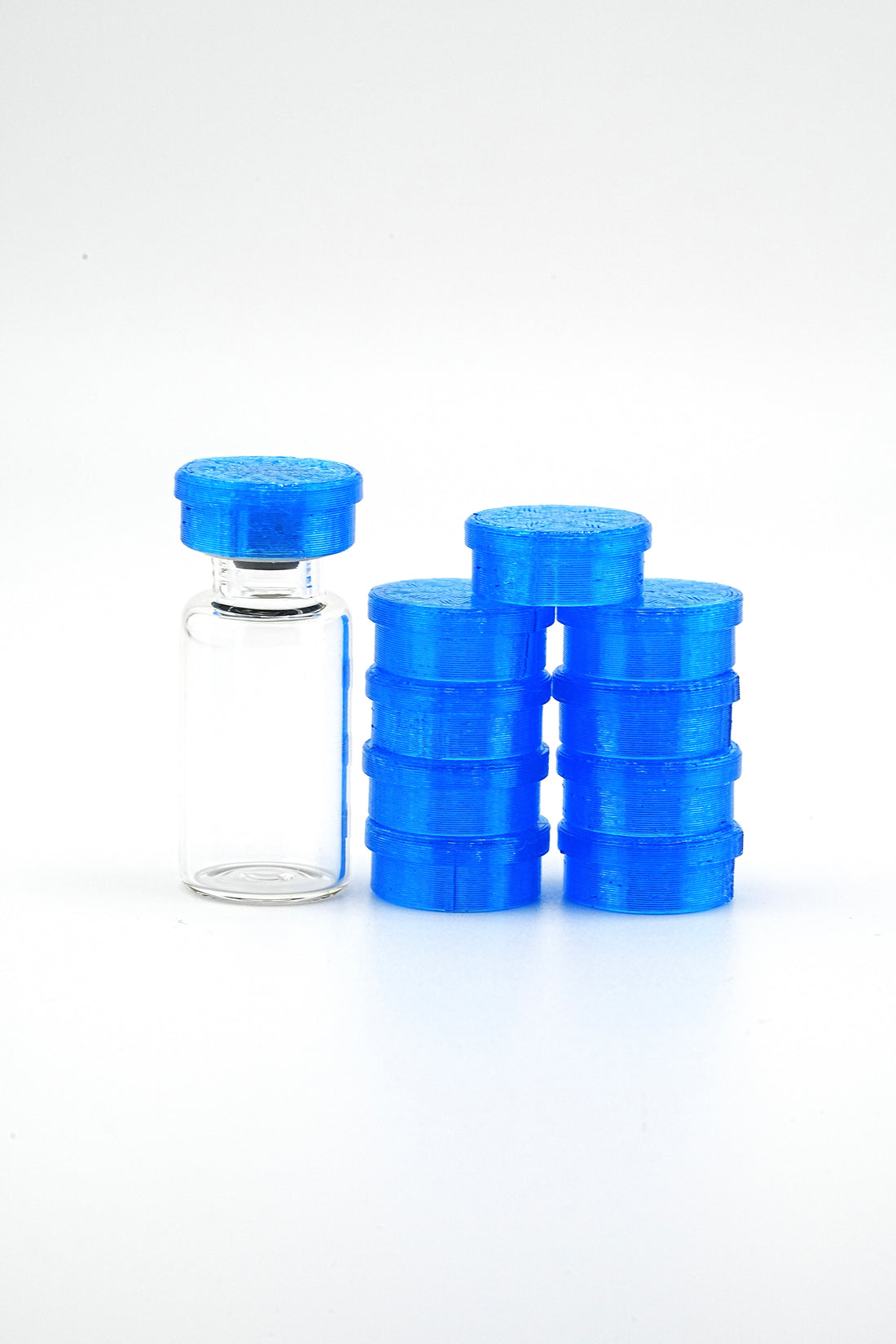 Clear glass vial with blue cap and multiple blue plastic containers on a white background