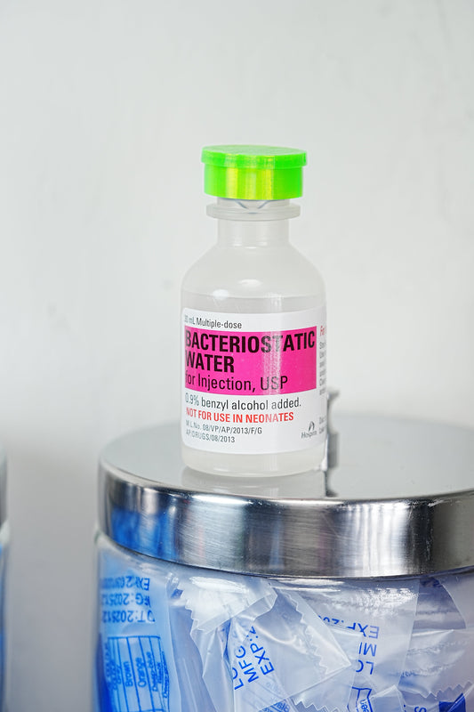 Where to buy peptide injection supplies — Hospira bacteriostatic water bottle resting on a glass jar of single-use alcohol prep pads