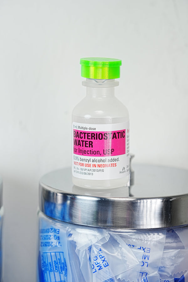 Where to buy peptide injection supplies — Hospira bacteriostatic water bottle resting on a glass jar of single-use alcohol prep pads