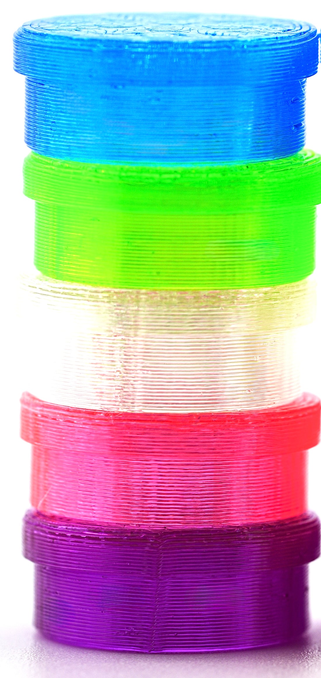 Stack of colorful vial caps in blue, green, pink, and purple on a white background