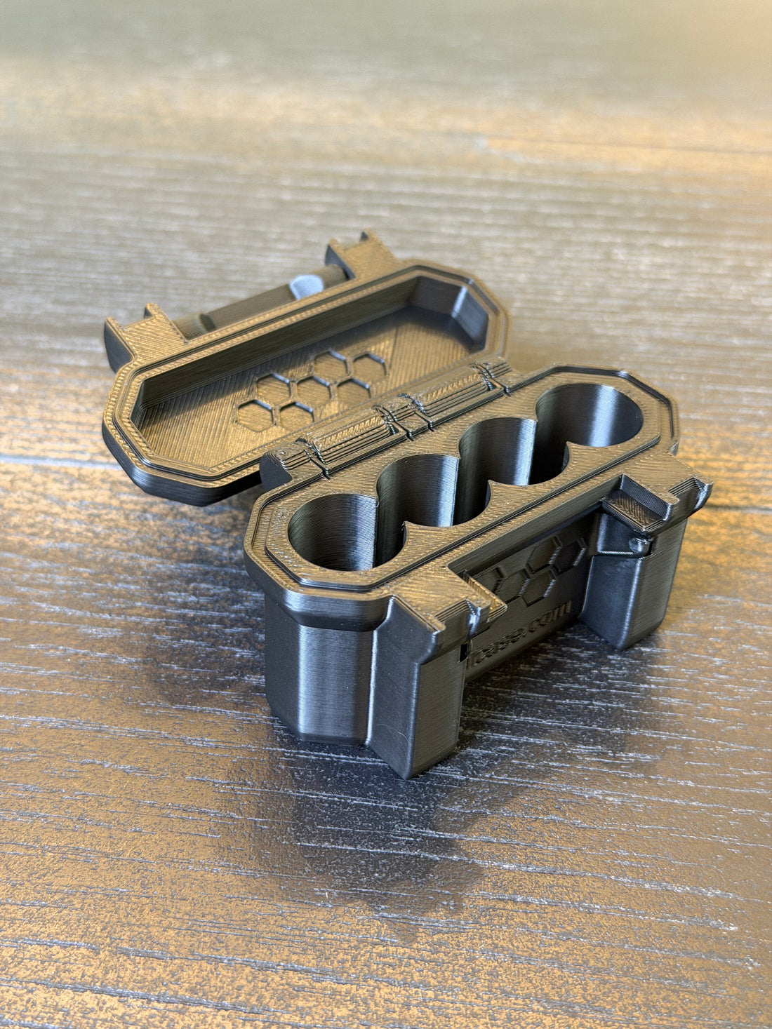 Open black 3D-printed hard-shell vial case with four interior slots and hinged lid viewed from above.
